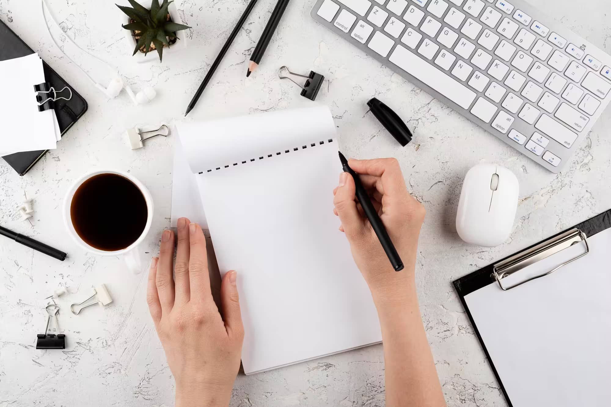 Person writing on a notepad at modern workspace