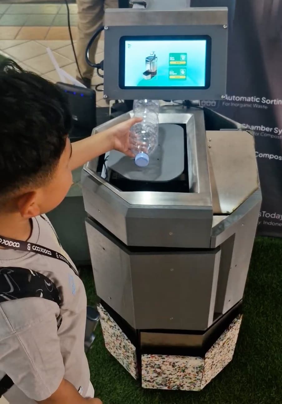 Child placing a plastic bottle into the Srikandi smart waste bin