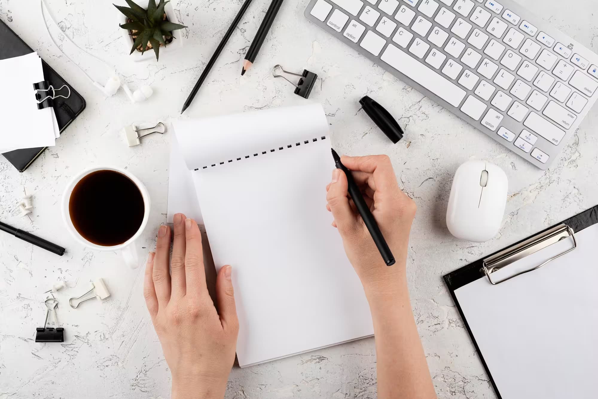Person writing on a notepad at modern workspace